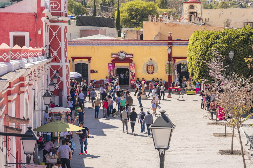 a crowd of people walking down a street next to a yellow building