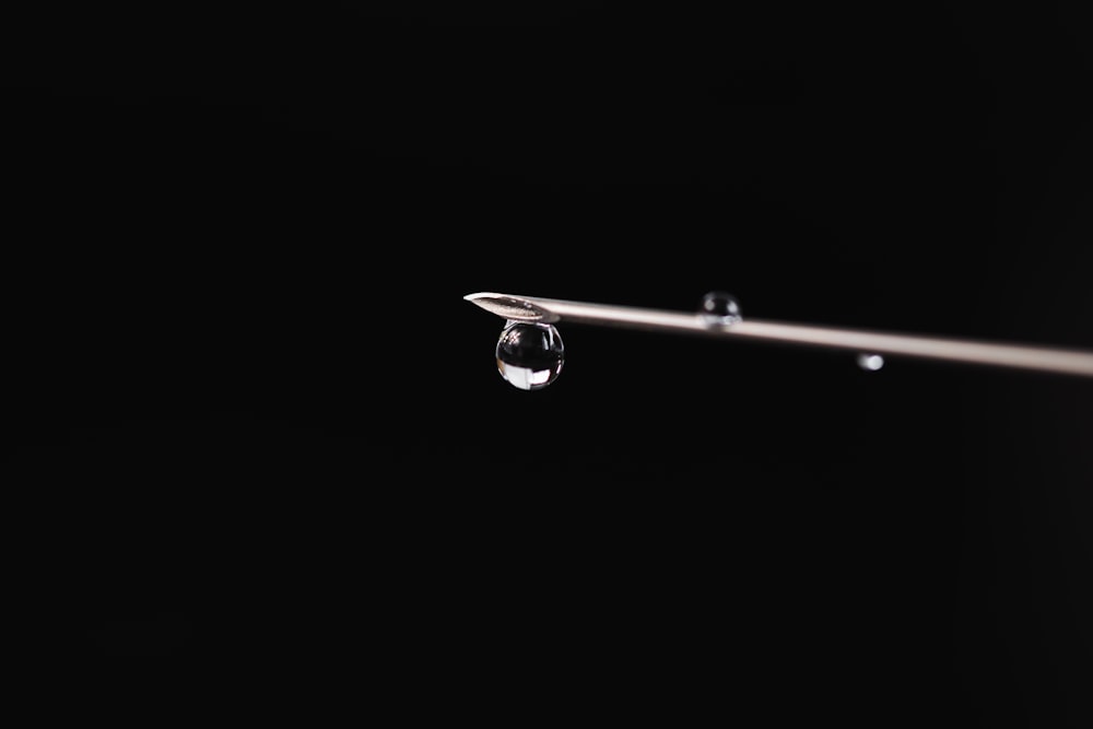 a drop of water hanging from a metal bar