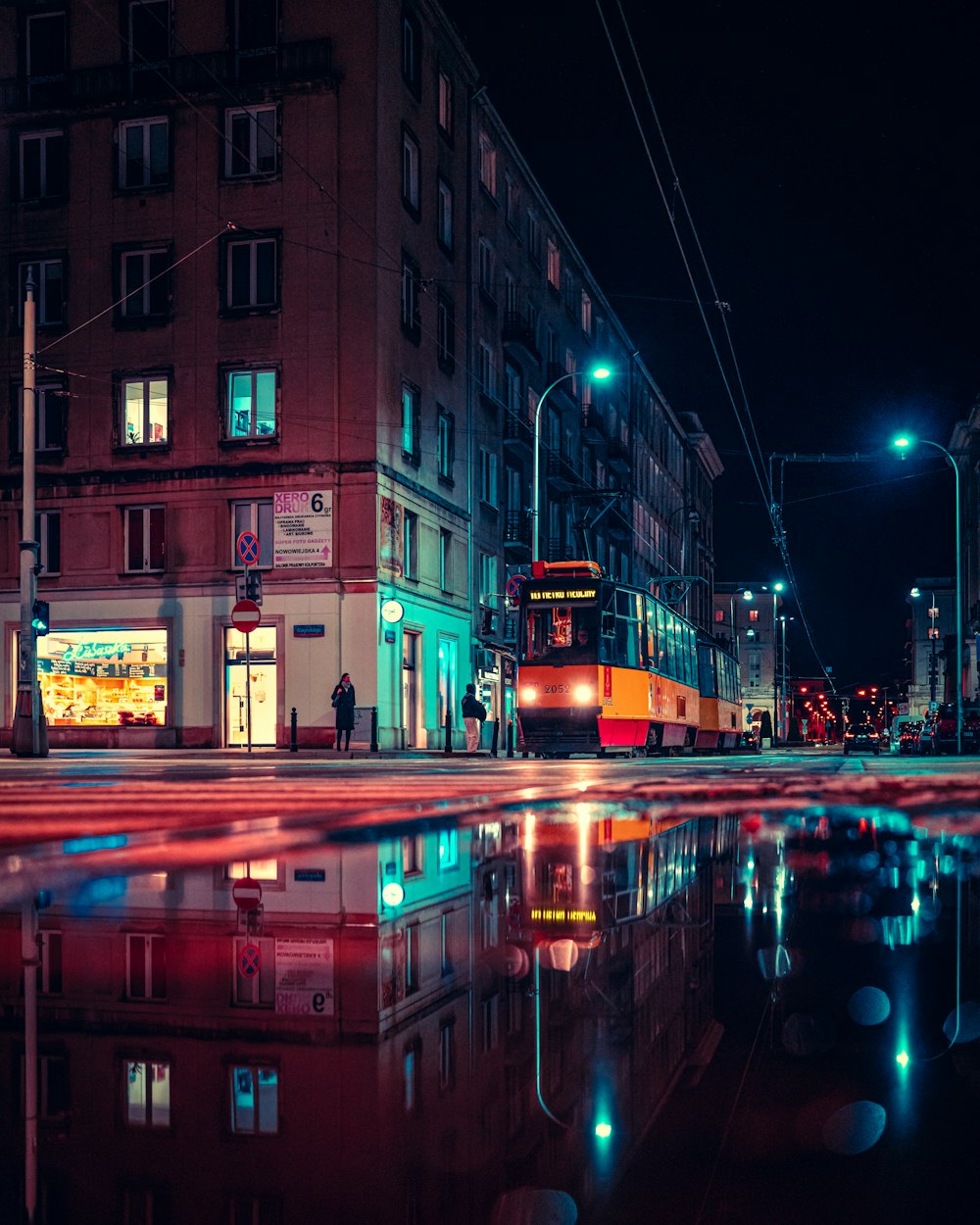 a red double decker bus driving down a street at night