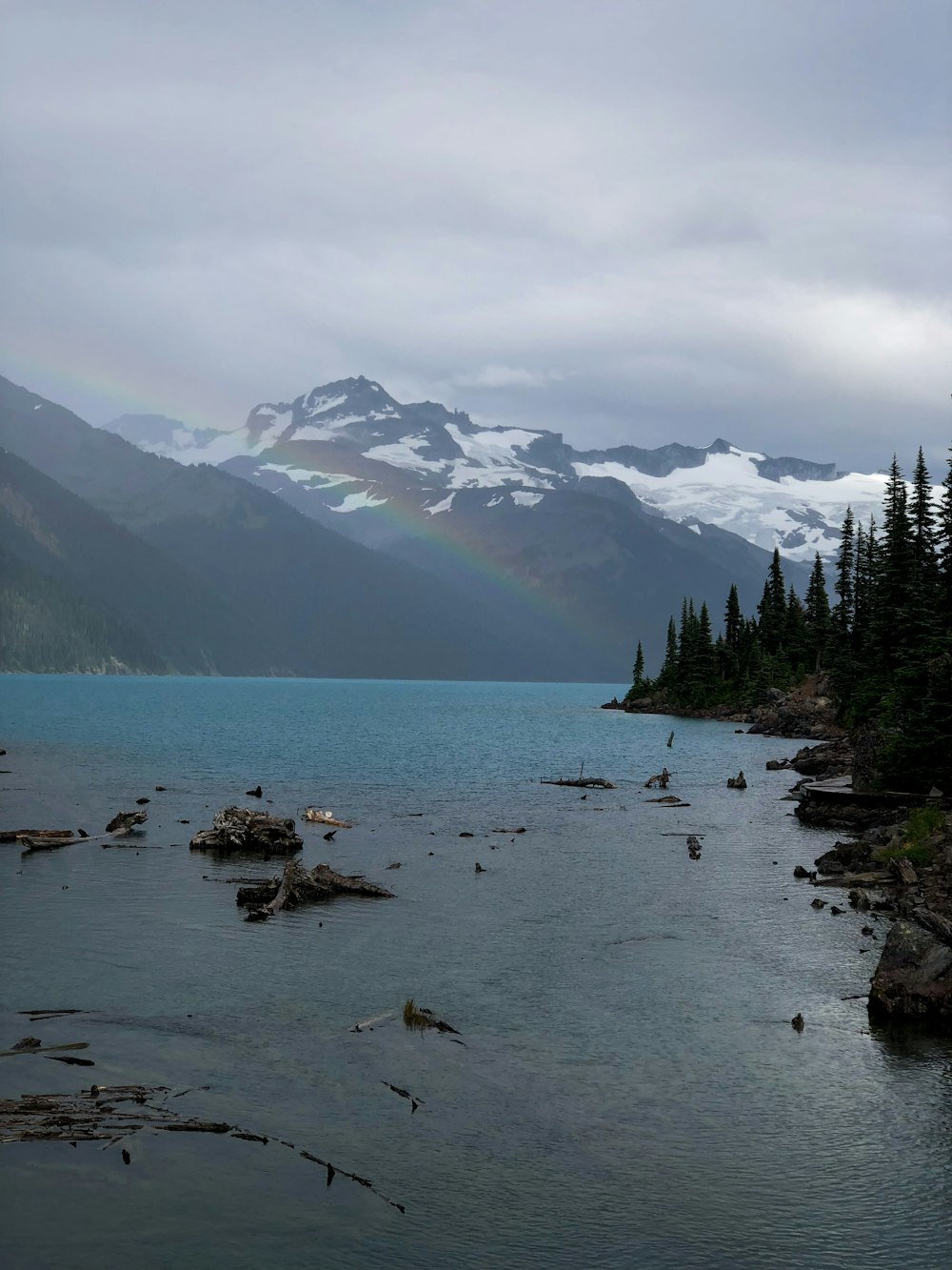 a rainbow shines in the sky over a mountain lake