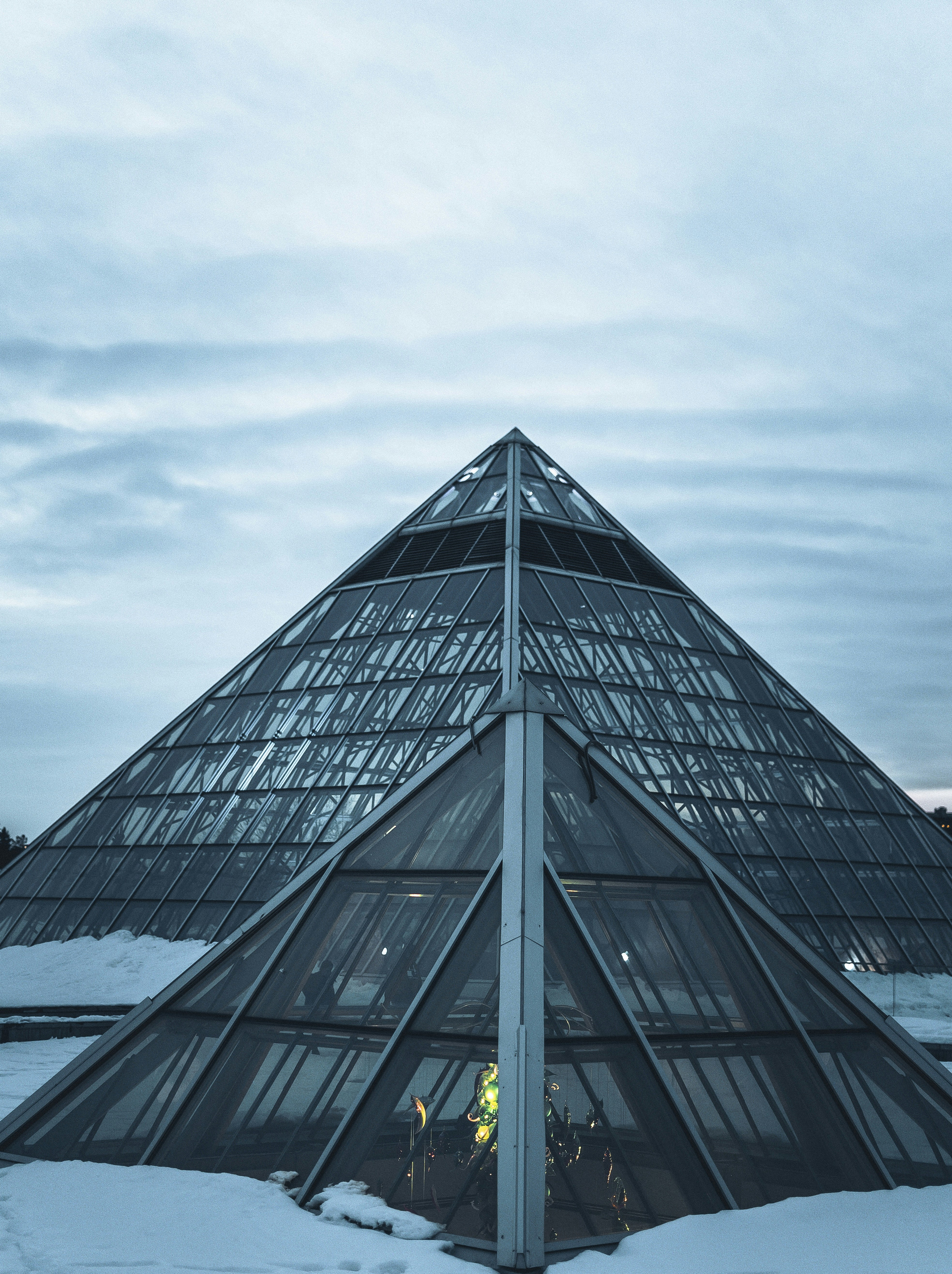 a very tall glass building with snow on the ground