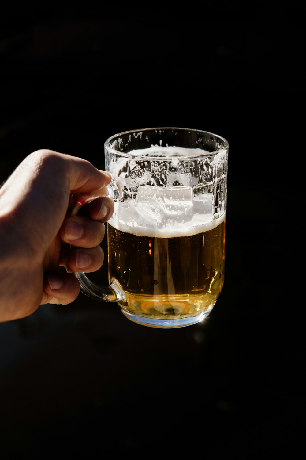 a person holding a glass of beer in their hand