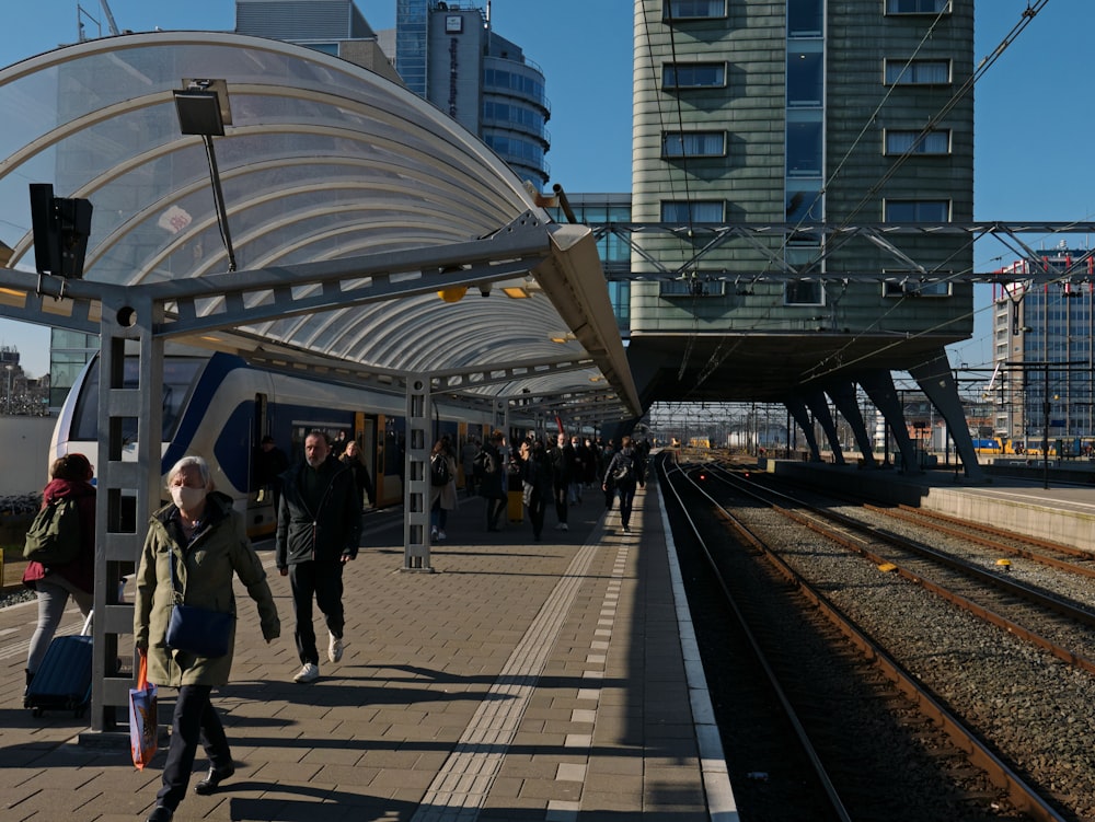 a group of people walking along side of a train station
