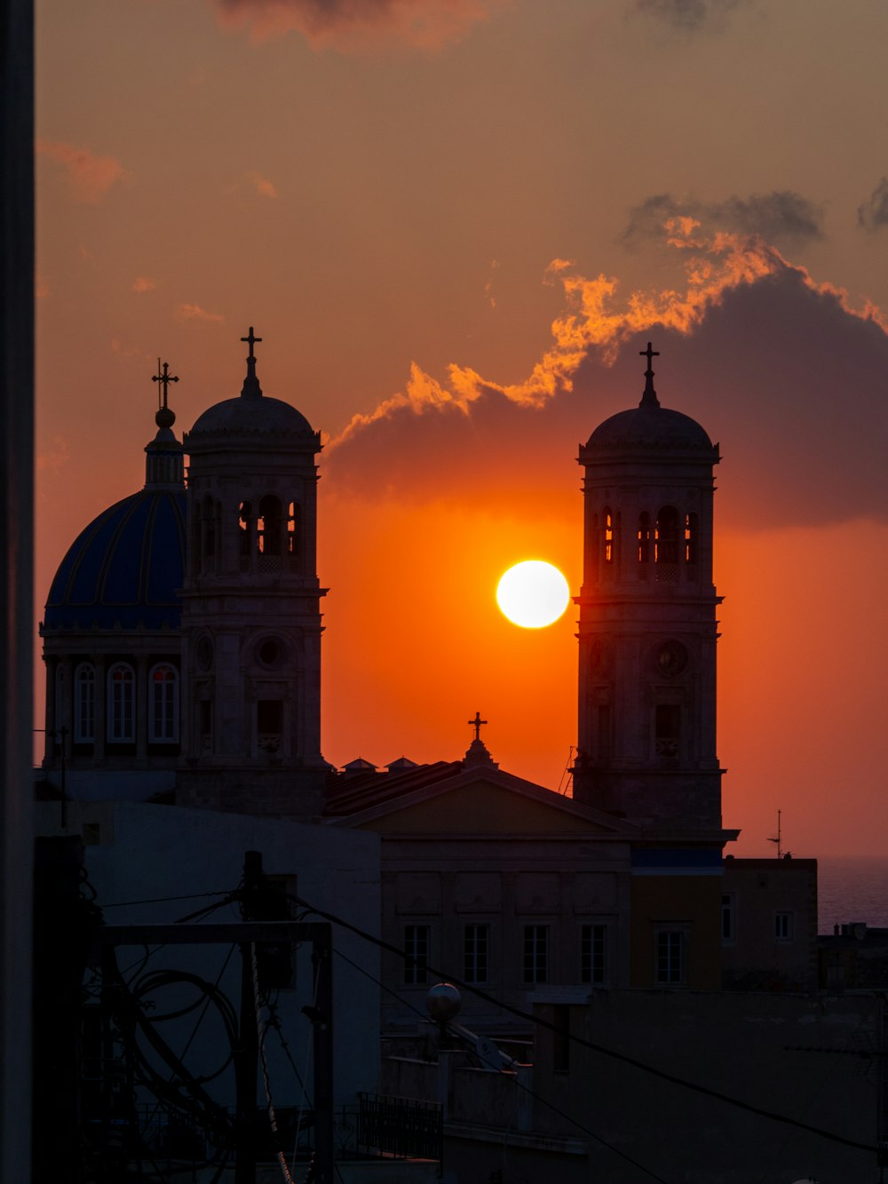 the sun is setting behind two large buildings