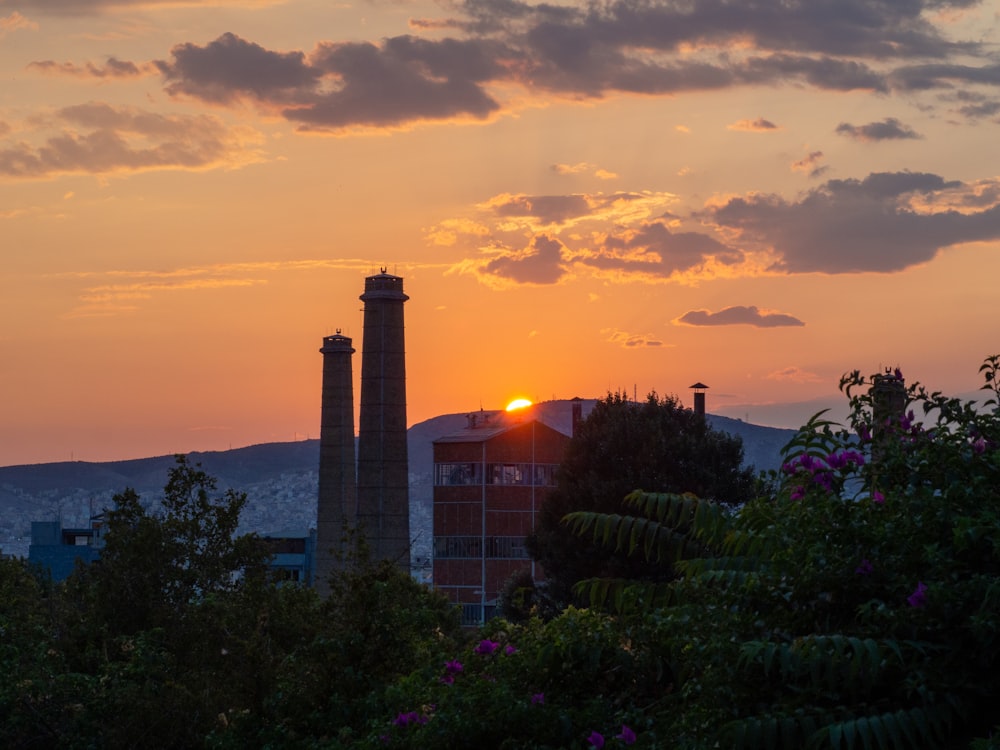 the sun is setting over a factory with smoke stacks