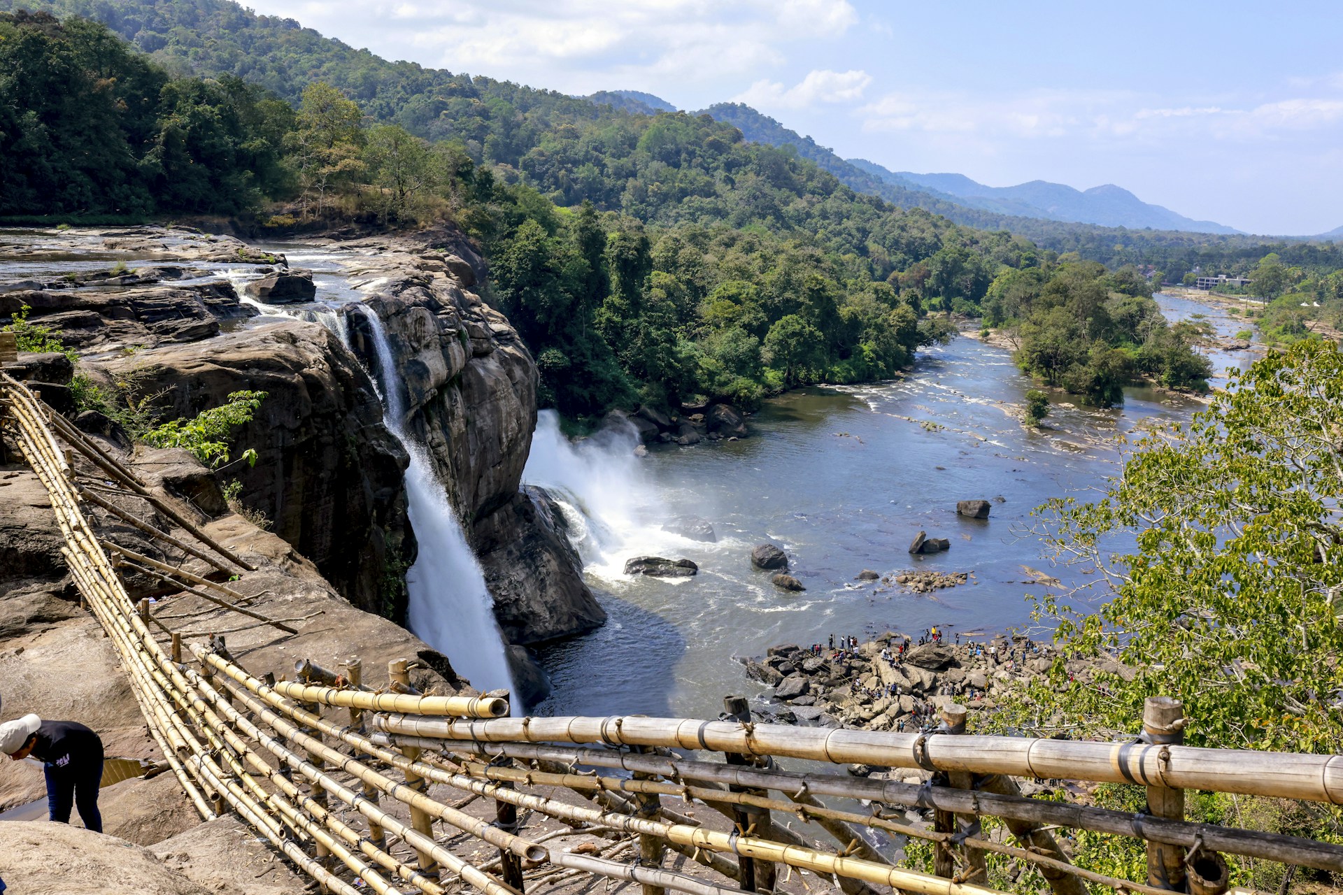 a man standing on a wooden bridge over a river