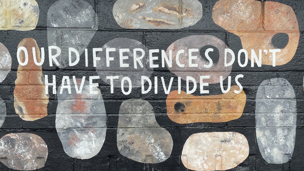 un mur de briques avec un message peint qui dit que nos différences n’ont pas à le faire