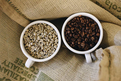 two white cups filled with coffee beans sitting on top of a couch