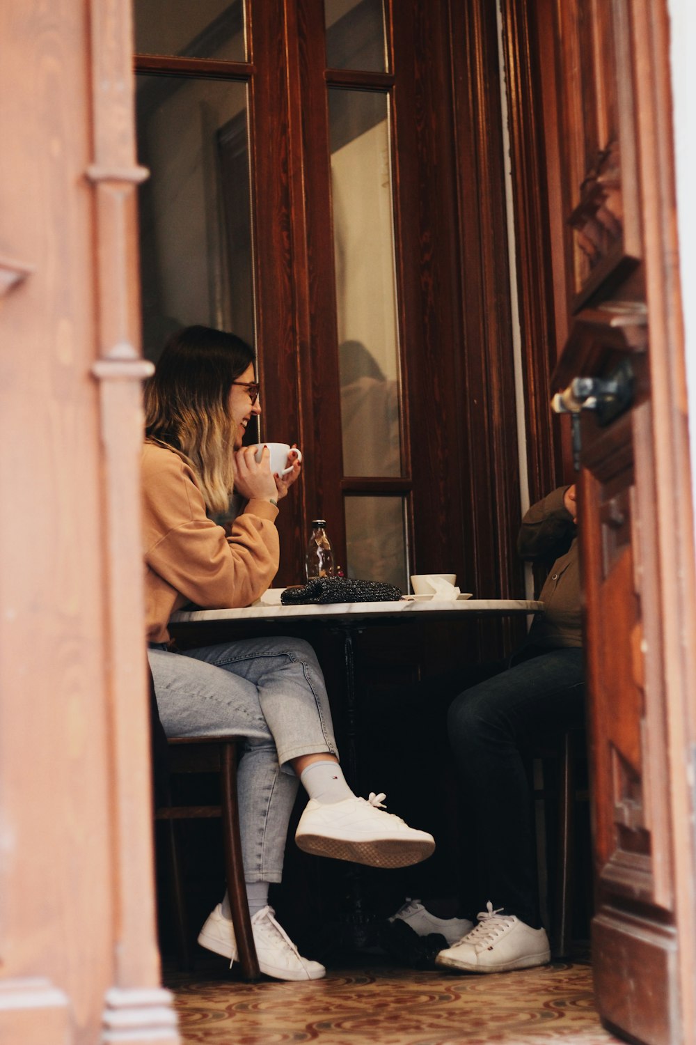 two women sitting at a table drinking coffee