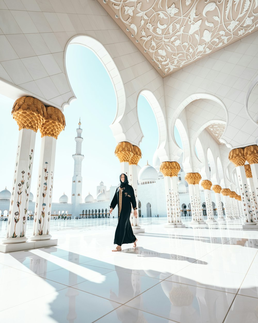 a woman in a black and white outfit is standing in a room with arches and