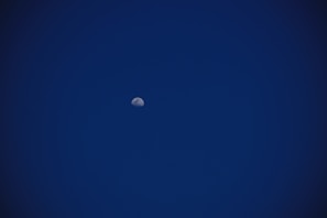 the moon is visible in the dark blue sky