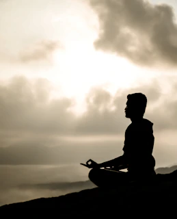 a man sitting on top of a hill while meditating