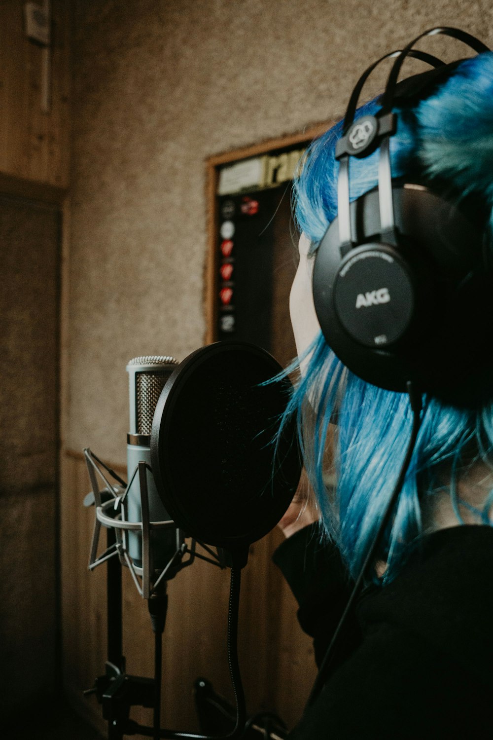 a woman with blue hair wearing headphones in a recording studio
