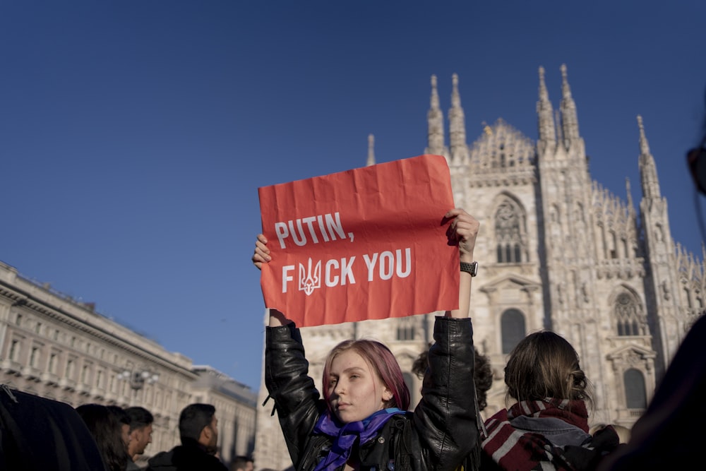 a woman holding a sign in front of a building