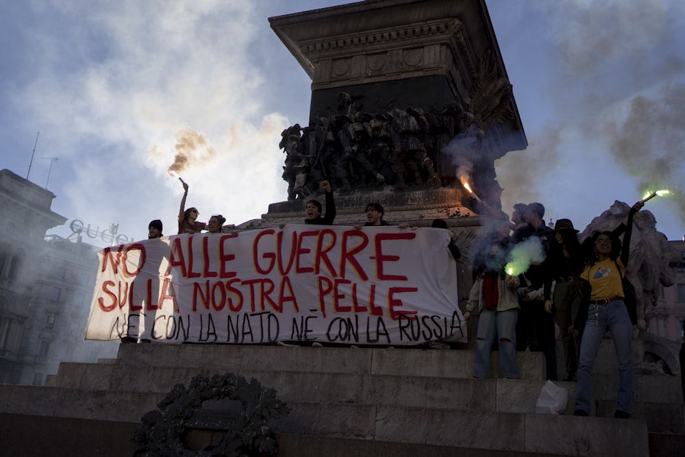 a group of people holding a sign on top of a monument