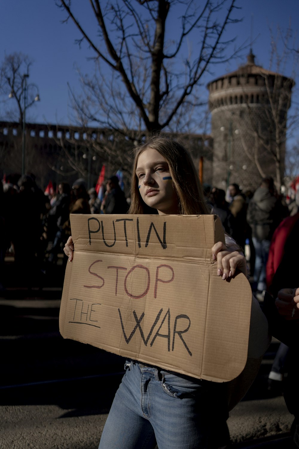 a woman holding a sign that says puttin stop the war