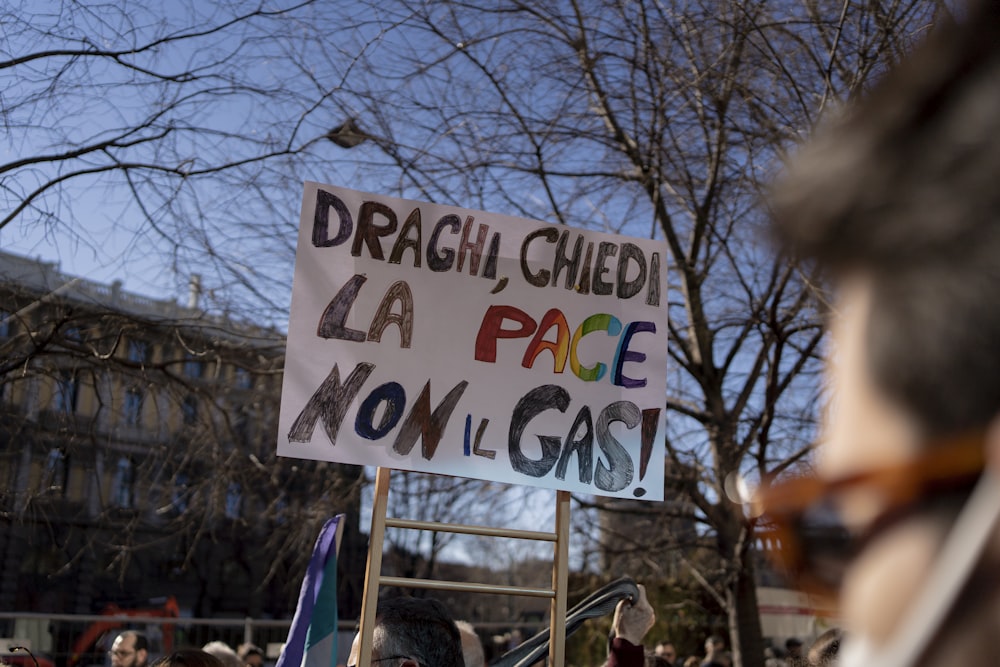 a protest with a sign that reads dragh cheed la page now gas