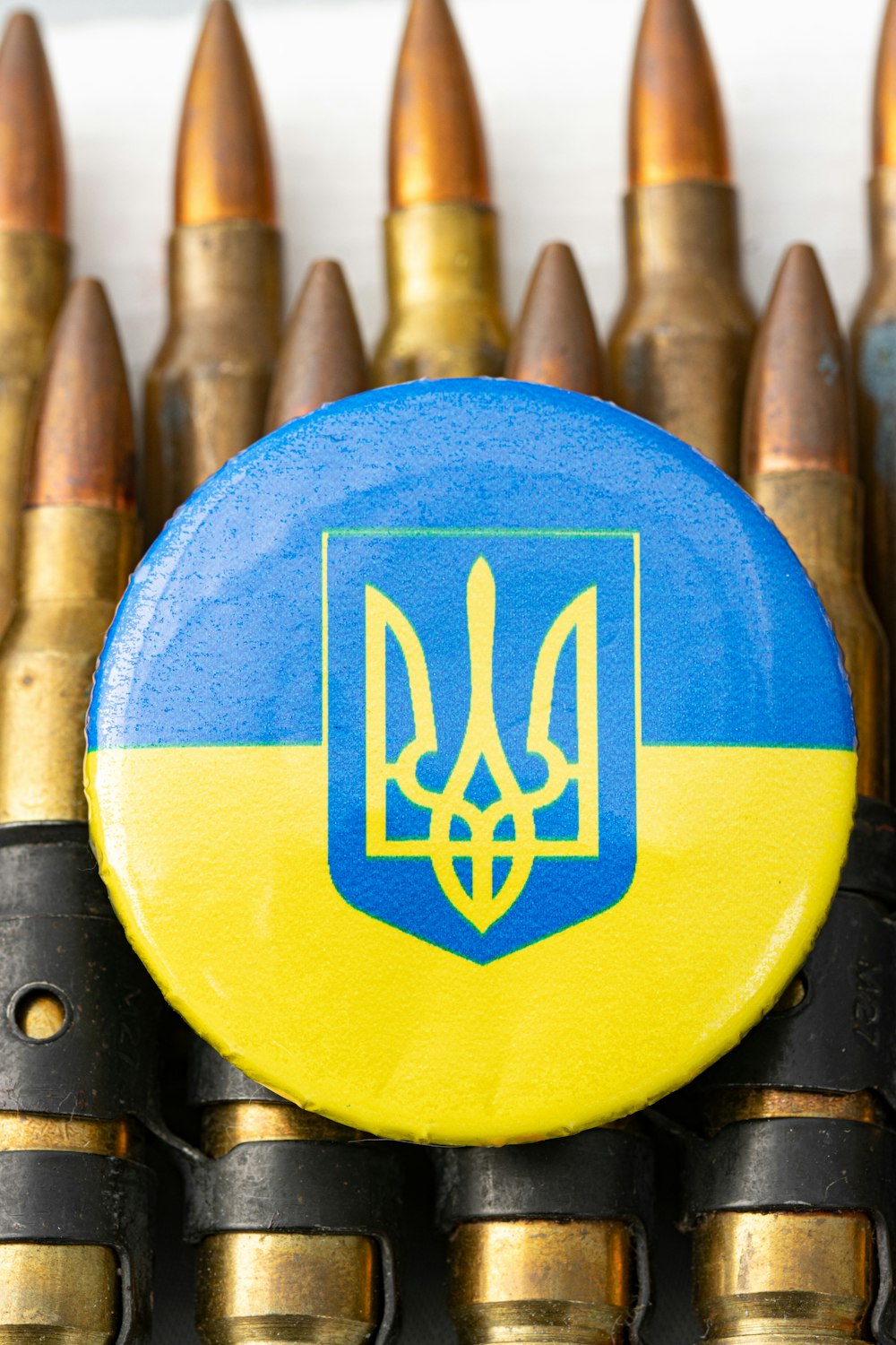 a blue and yellow button sitting on top of a bunch of bullet shells