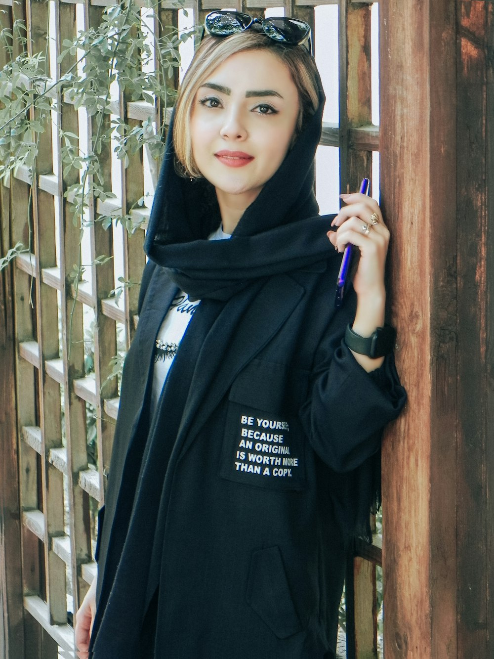 a woman in a black hoodie is holding a pen