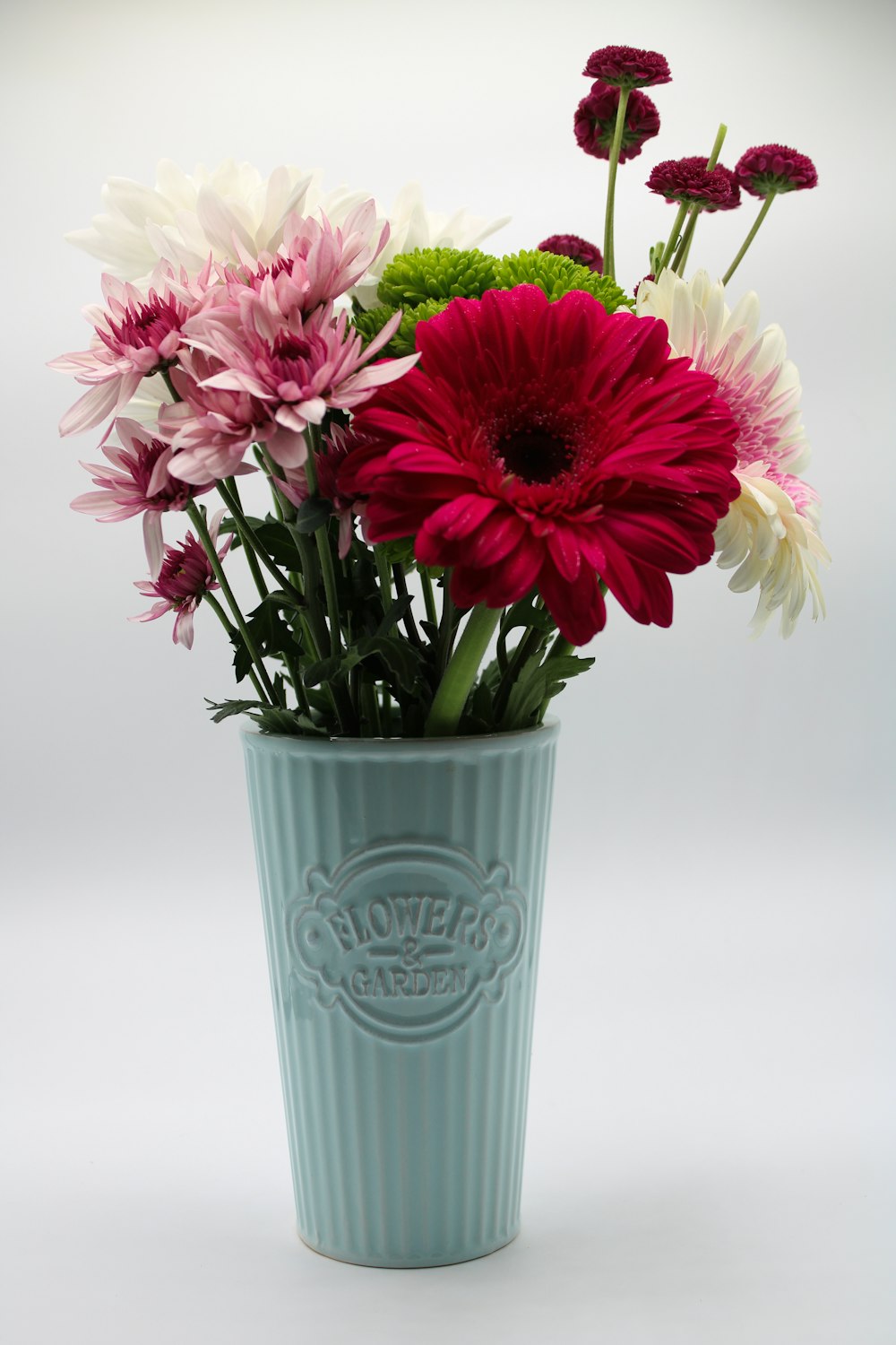 a vase filled with lots of different colored flowers