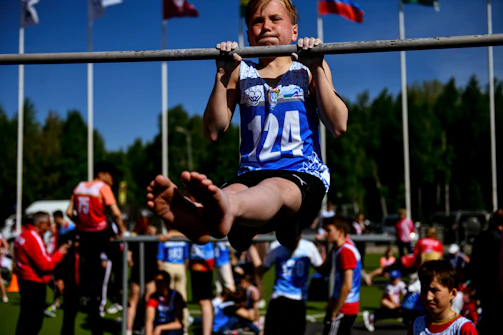 a young girl is doing a pull up on a bar