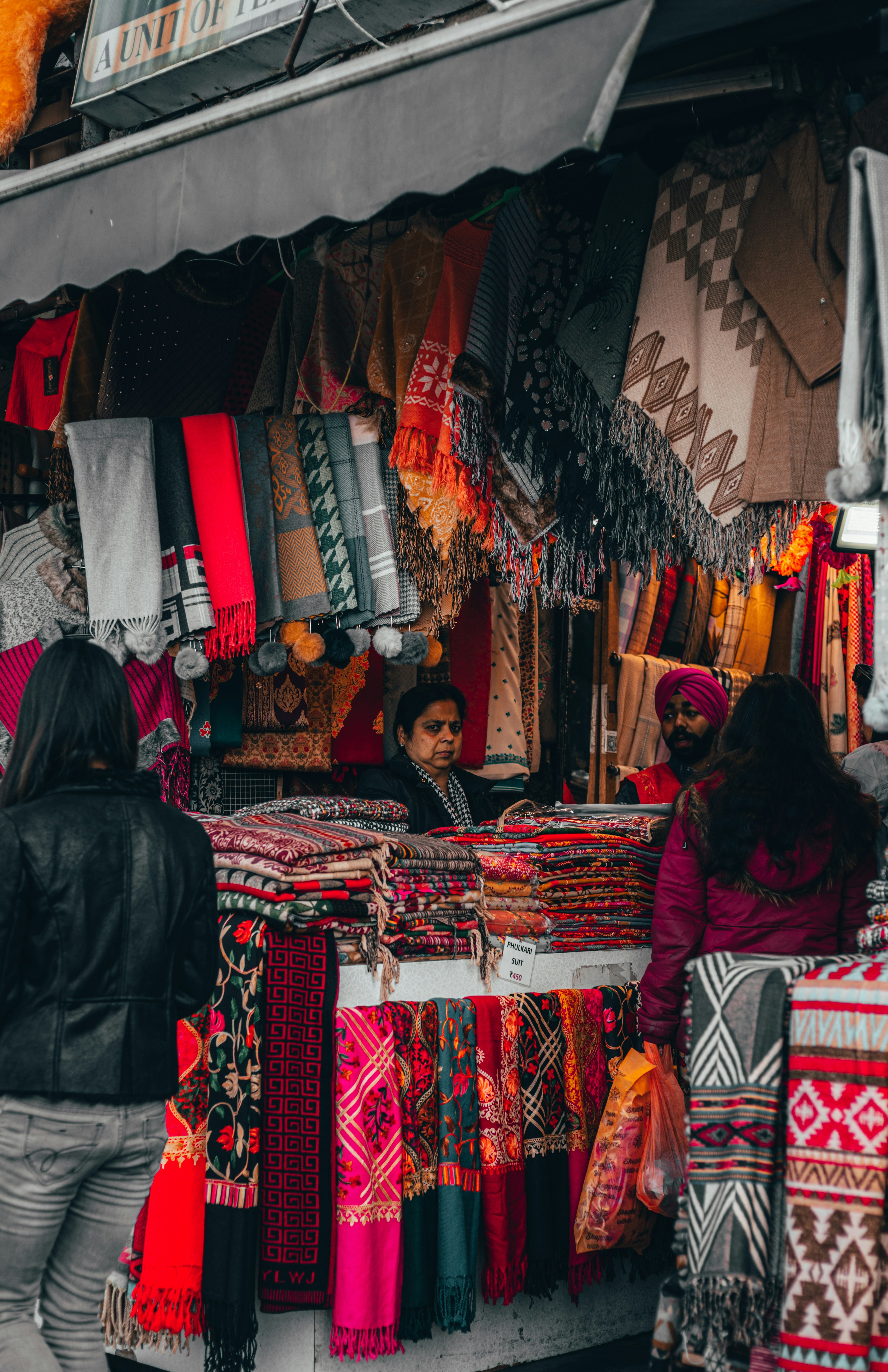 a woman standing in front of a colorful display of scarves