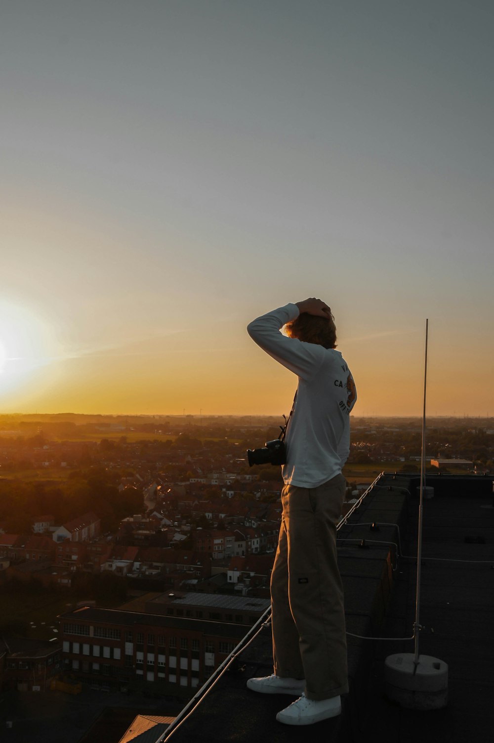 a man standing on top of a roof next to a tall building