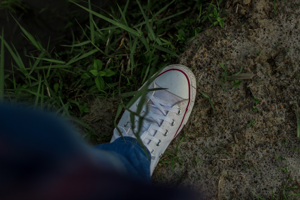 a person's white tennis shoe on the ground