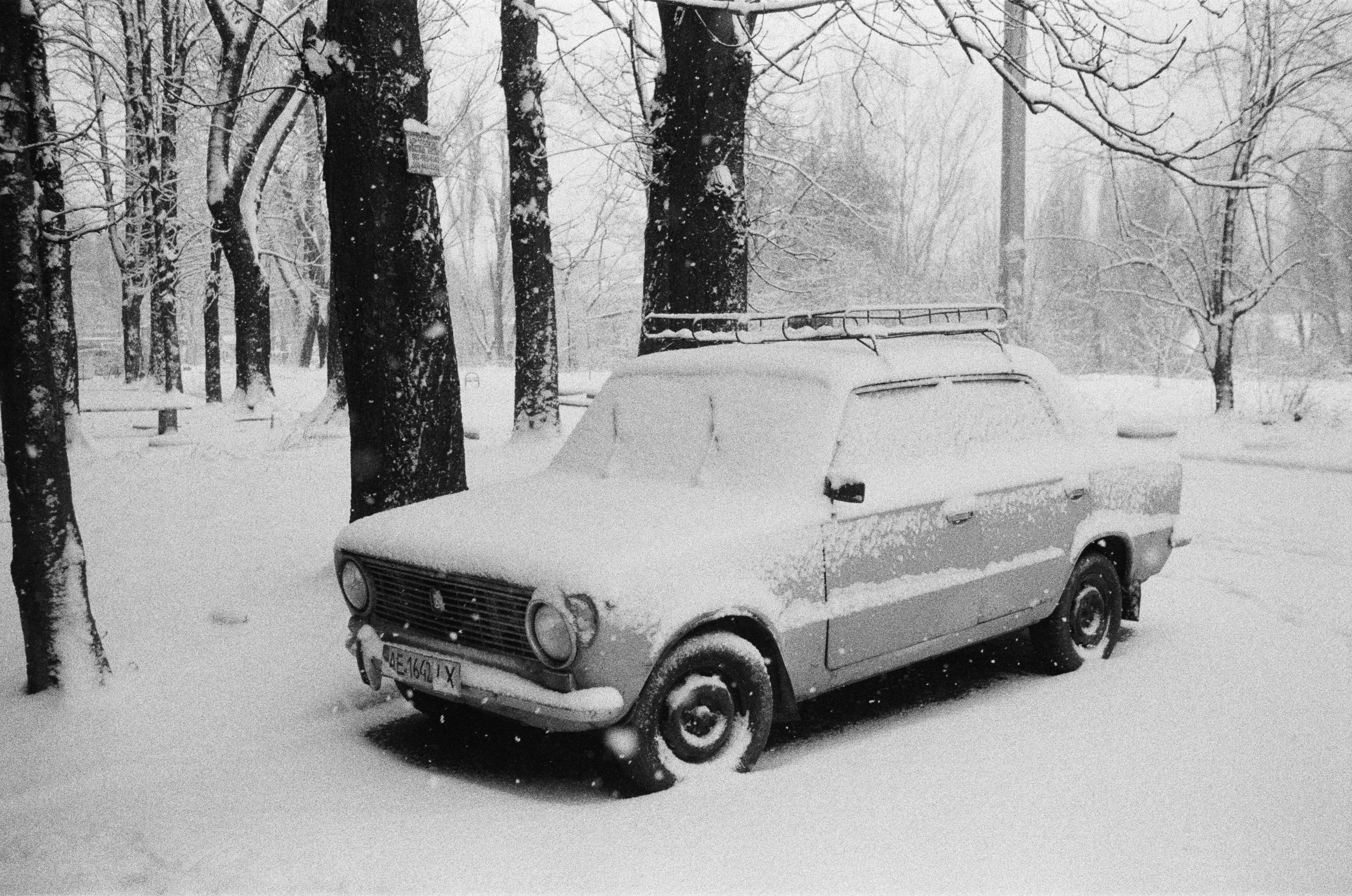 a car is parked in the snow in a wooded area