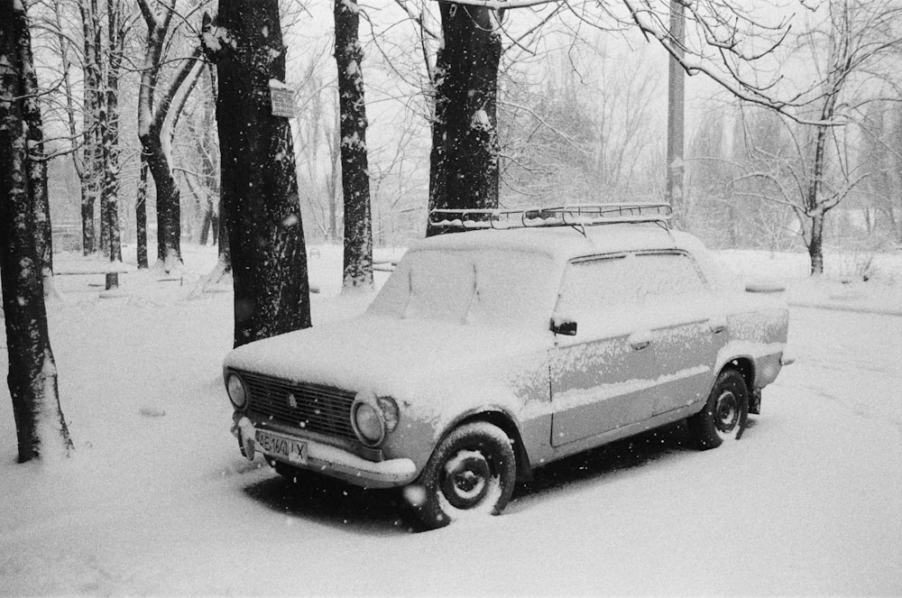 a car is parked in the snow in a wooded area