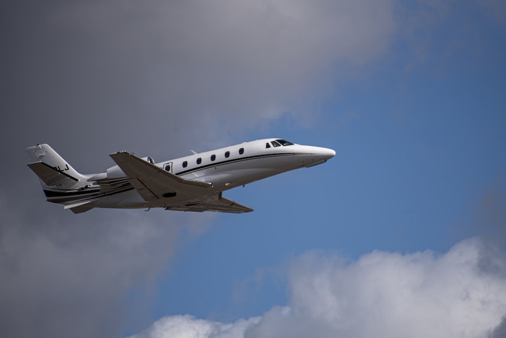 a small plane flying through a cloudy blue sky