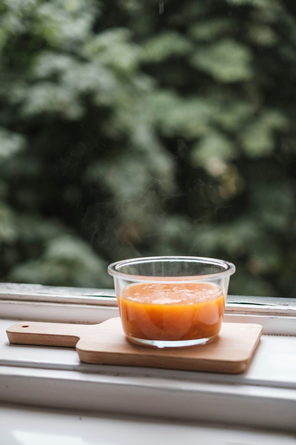 a cup of orange juice sitting on top of a window sill