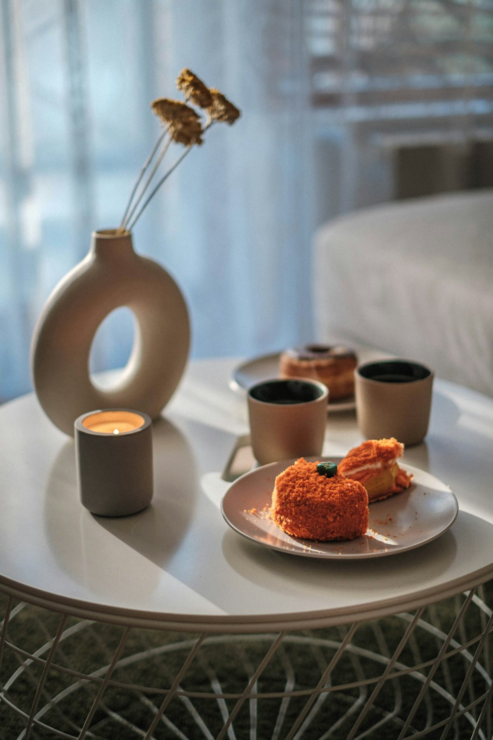 a white table topped with a plate of food and cups