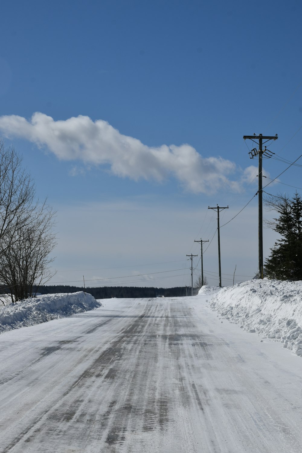 eine schneebedeckte Straße mit Stromleitungen und Telefonmasten