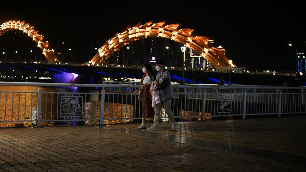 two people standing next to each other near a bridge