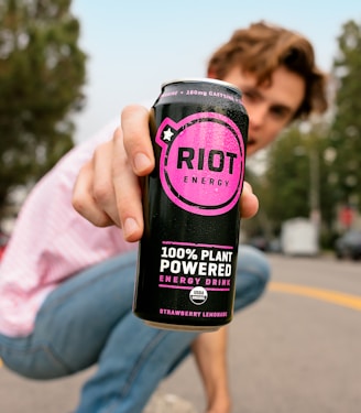 a man squatting down holding a can of riot energy