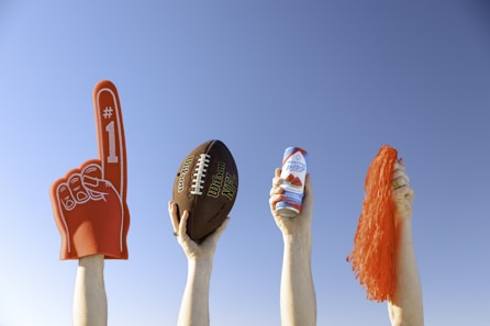 a group of people holding up footballs and a drink