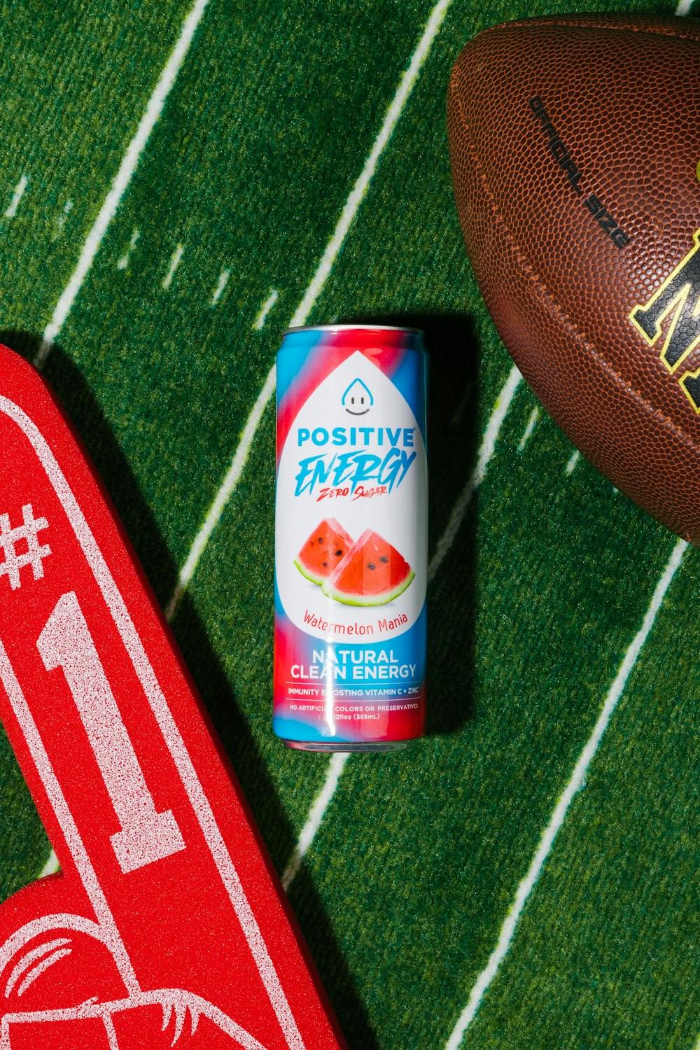 a can of watermelon next to a football on a field