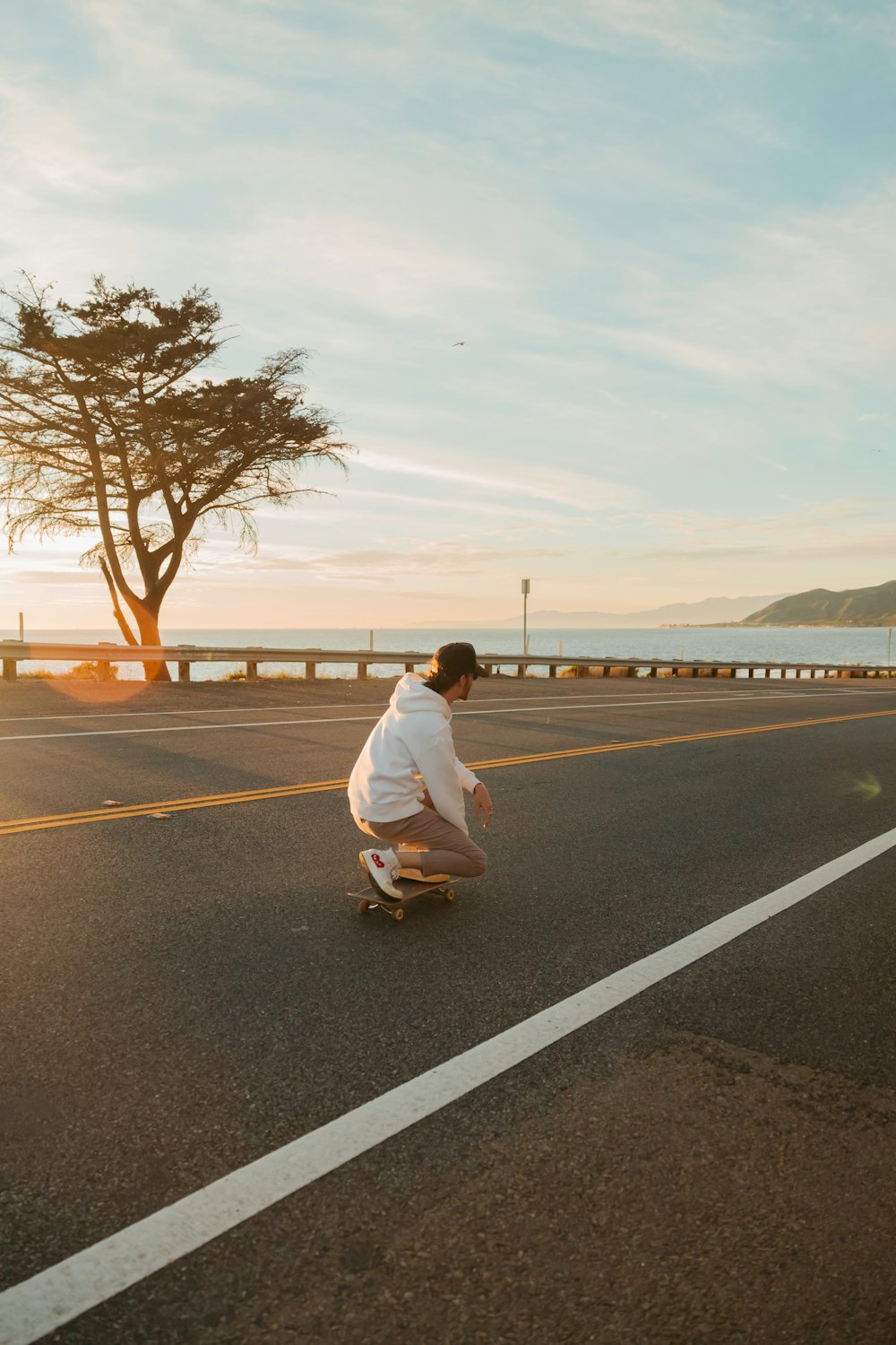 a man riding a skateboard down a street next to a tree