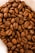 A close-up view of a pile of roasted coffee beans, showcasing their rich brown color and textured surface. The beans are tightly packed together, with visible creases and natural imperfections, emphasizing their freshness and quality.