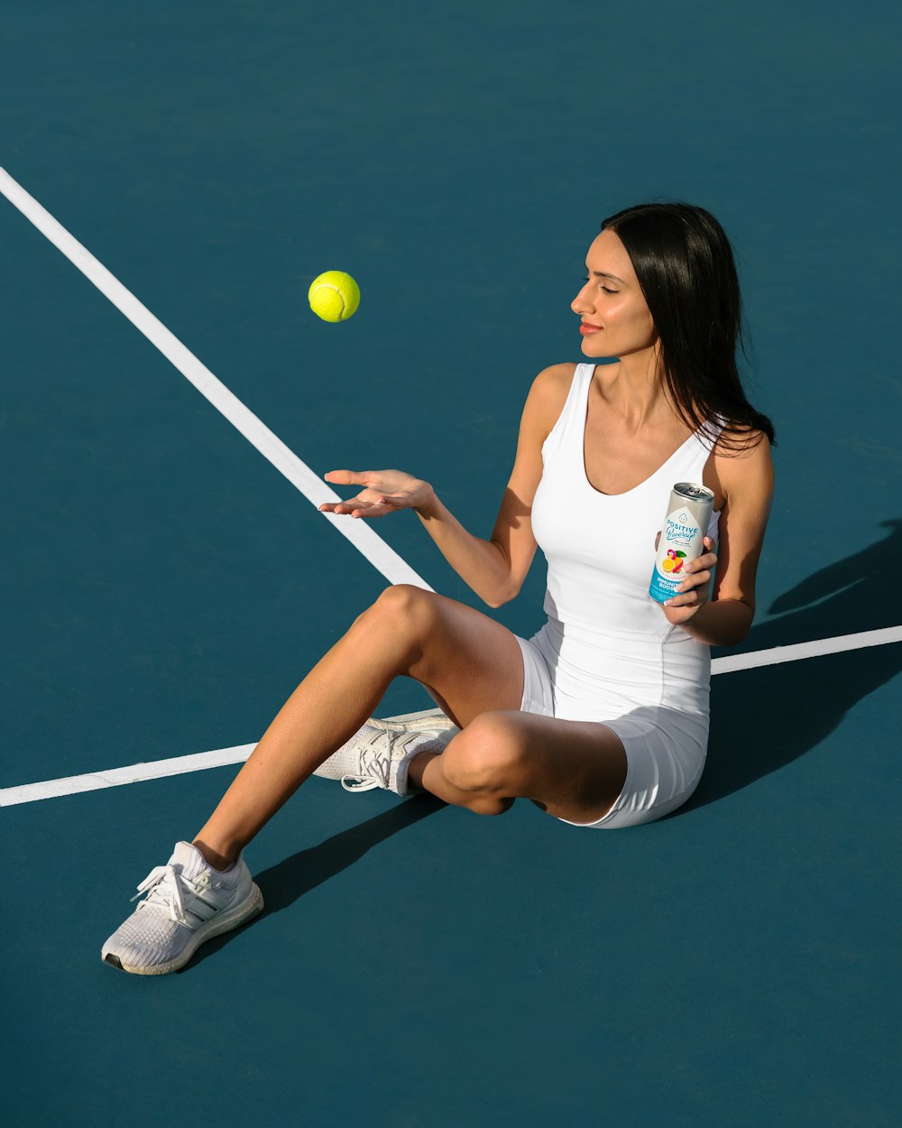 una donna seduta su un campo da tennis con in mano una racchetta da tennis