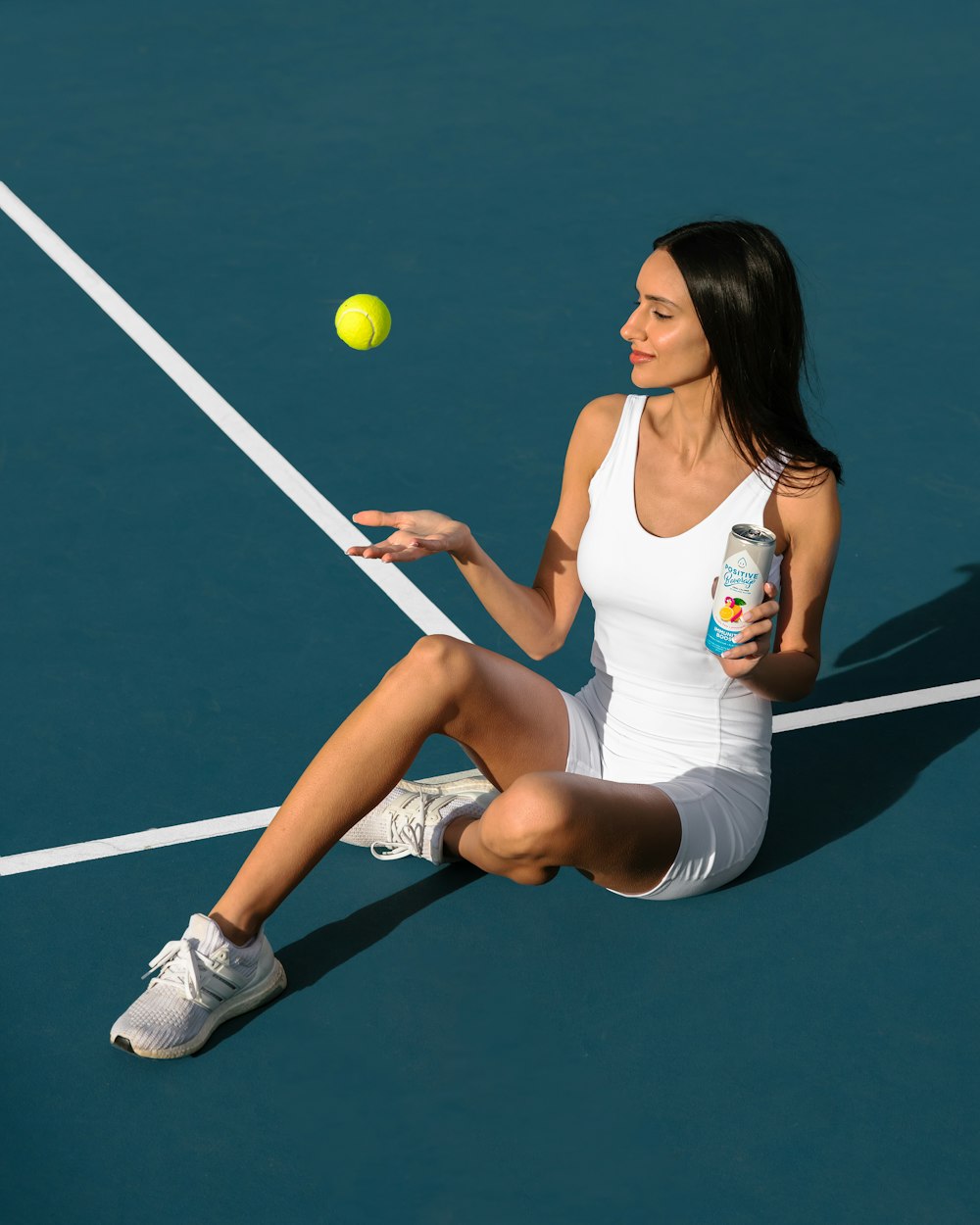 a woman sitting on a tennis court holding a tennis racquet