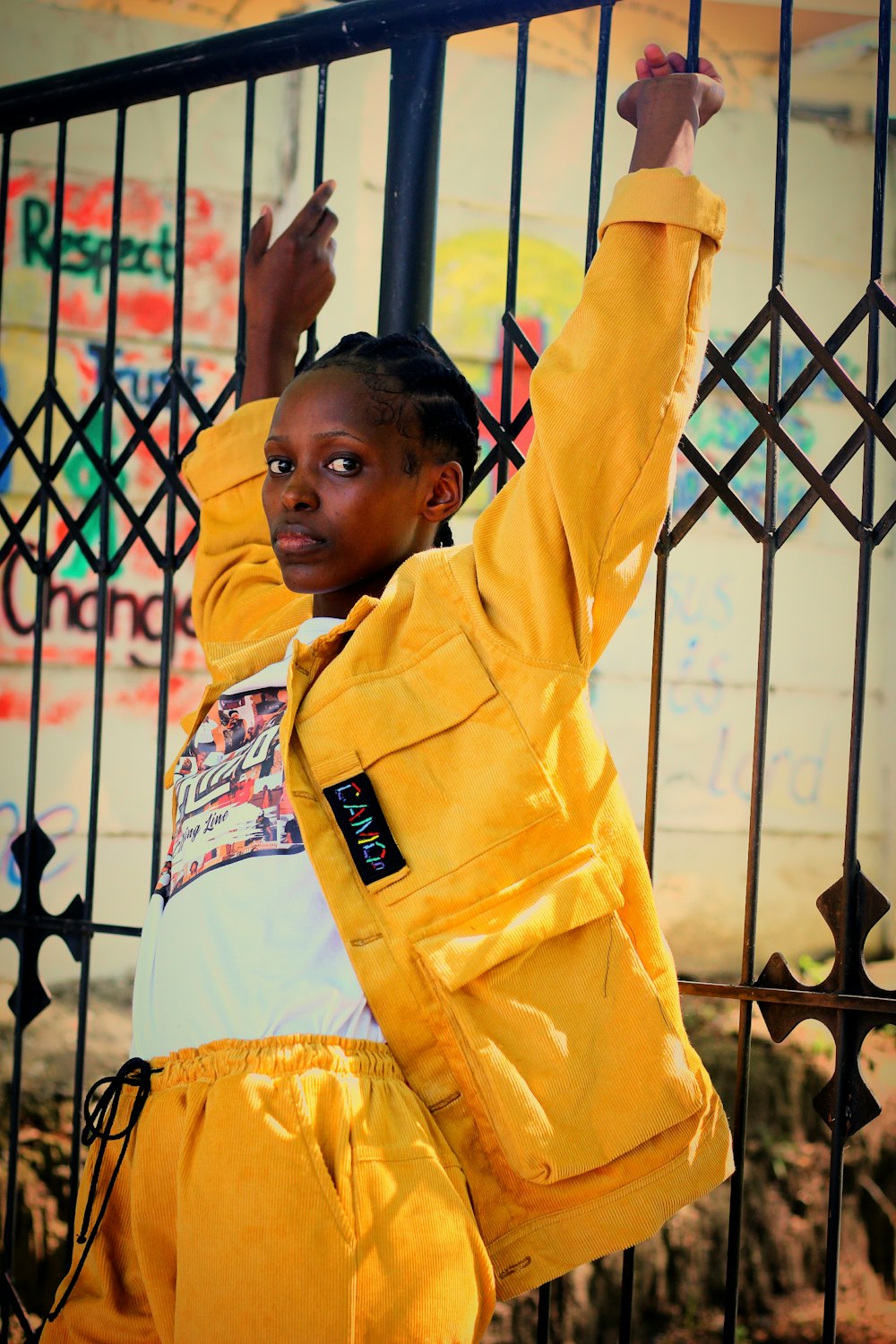 a young girl in a yellow jacket leaning on a fence