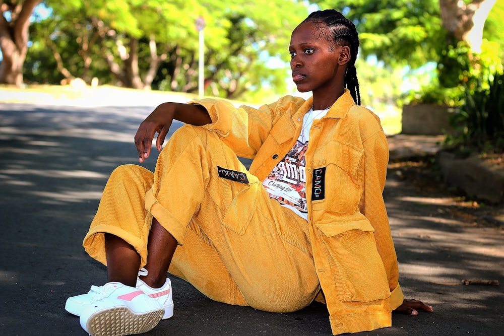 a woman in a yellow jumpsuit sitting on the ground