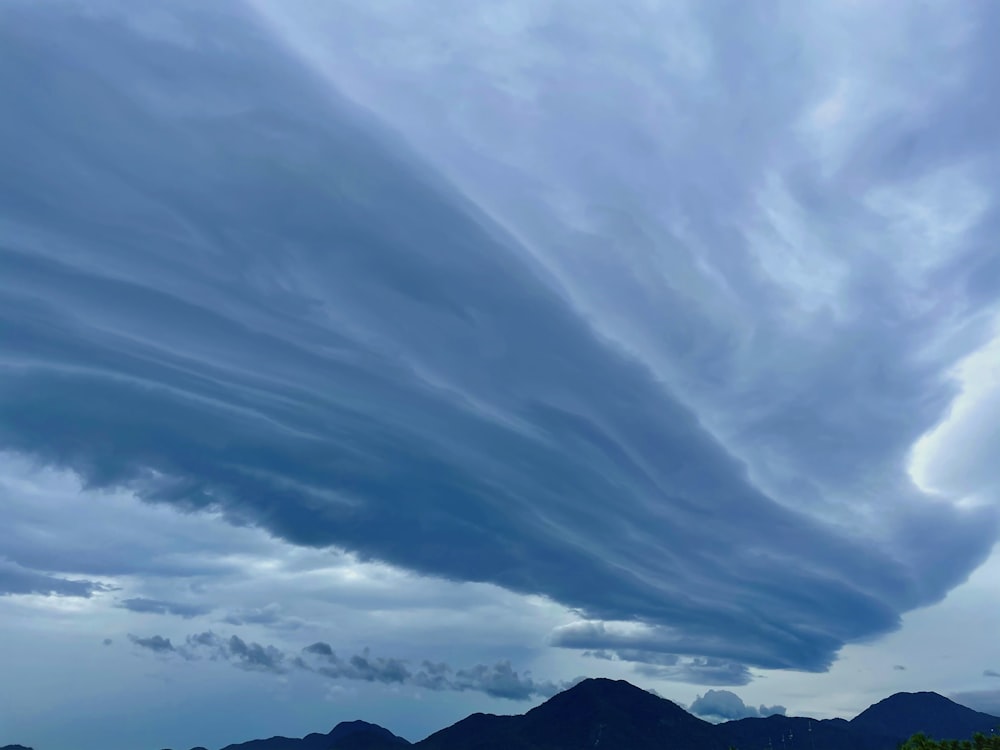 a cloudy sky with mountains in the background