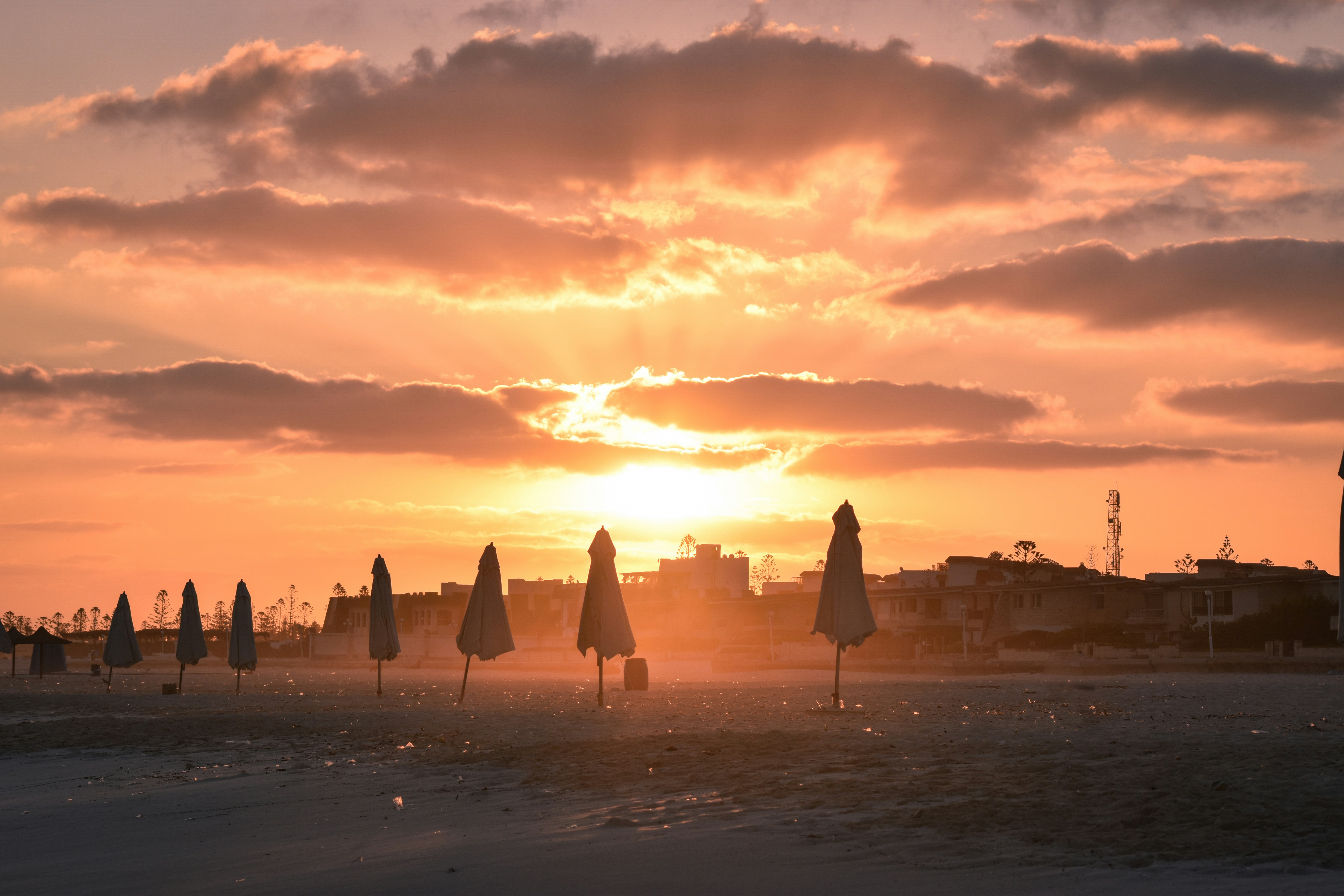 a beach with umbrellas and buildings in the background
