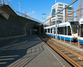 a blue and white train traveling under a bridge
