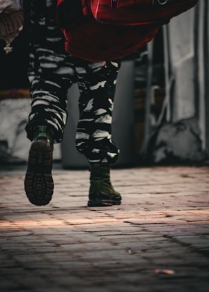 a person wearing camouflage pants and a red backpack