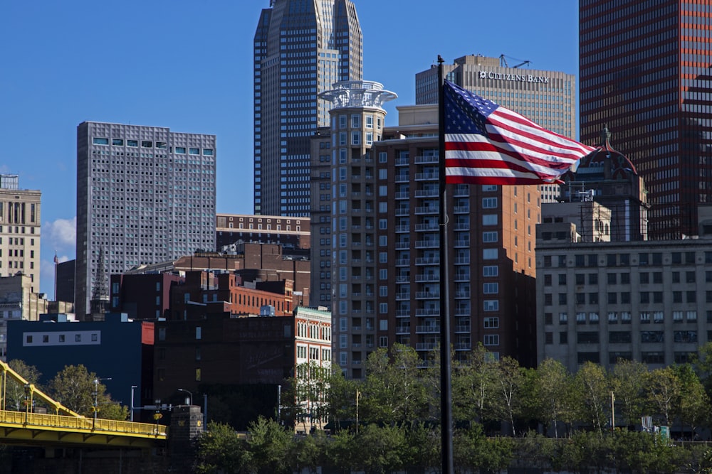 an american flag flying in front of a city skyline