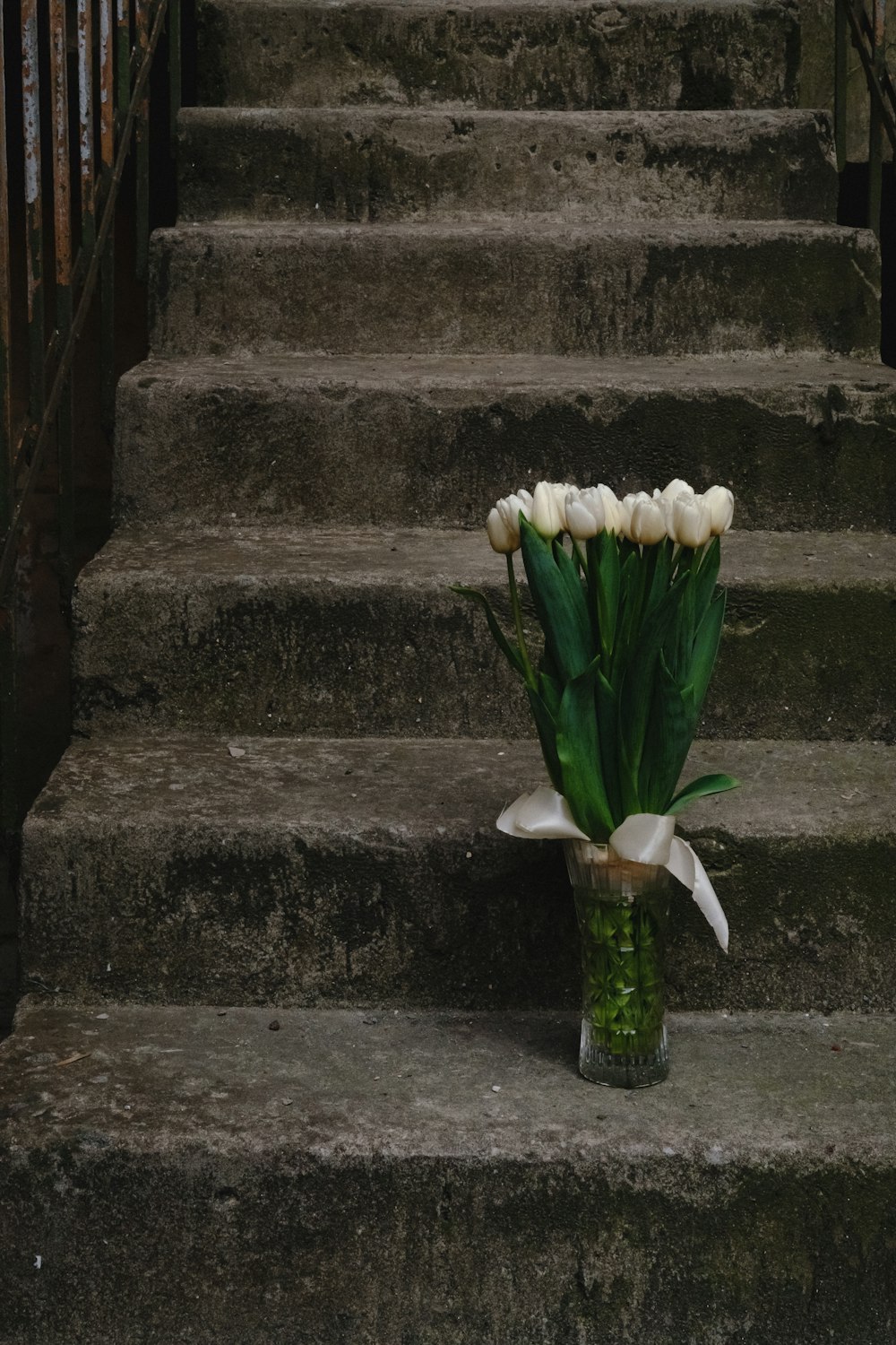 a bouquet of white tulips sitting on a set of stairs